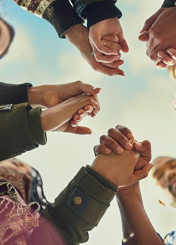 Shot of a group of friends putting their hands together in prayer